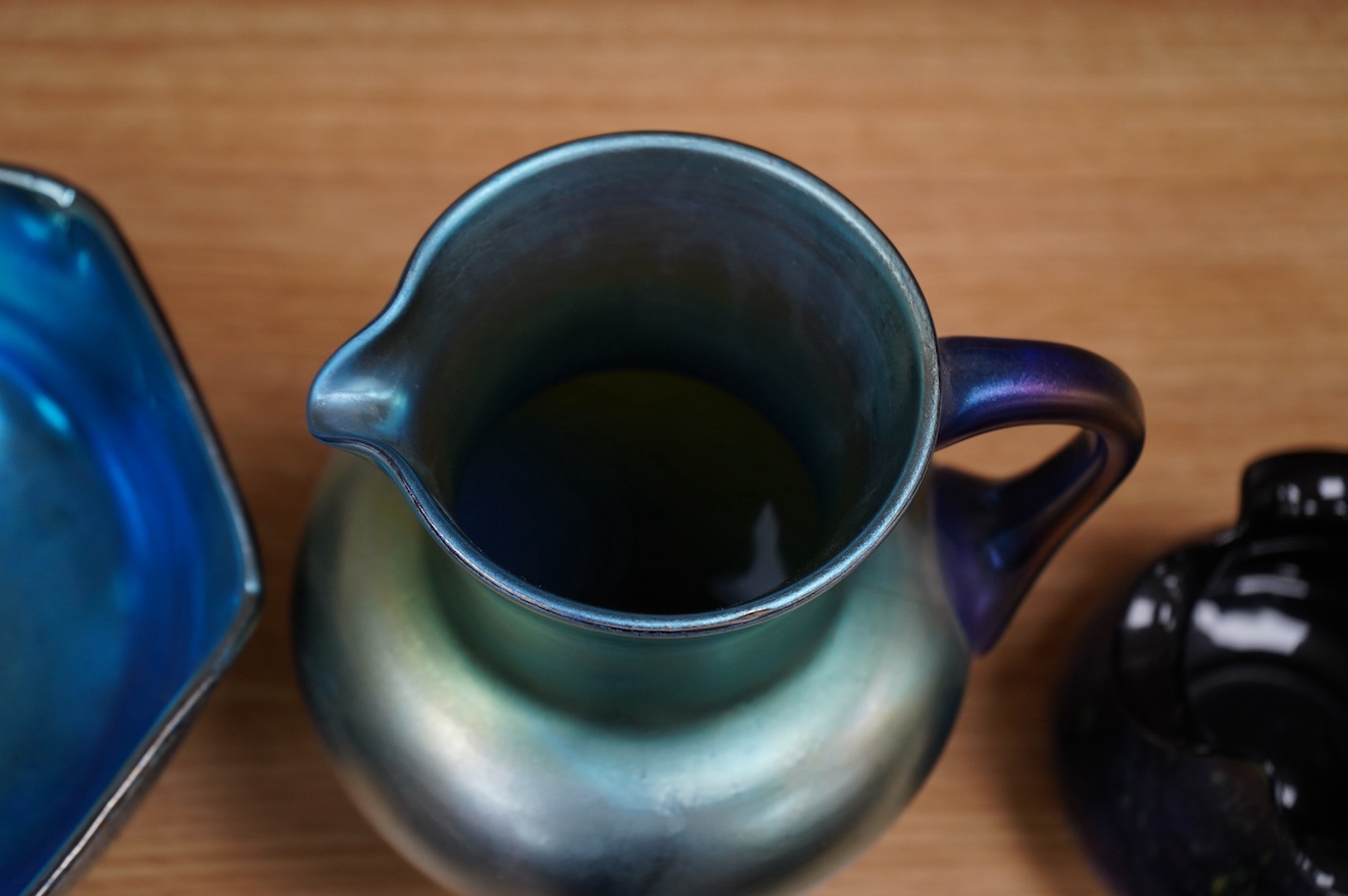 A Loetz cobalt Papillon iridescent glass footed hexagonal bowl, a Kralik blue iridescent vase and a large Bohemian iridescent glass jug (3) tallest 21cm. Condition - good